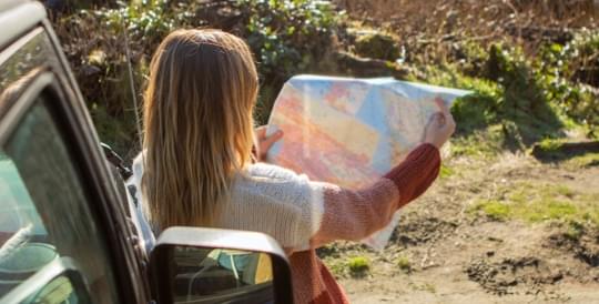 Woman holding a map - link to view insurance info by state from The General Insurance quote page.