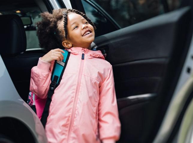 Young girl ready to get into car and go to school - link to cheap car insurance information