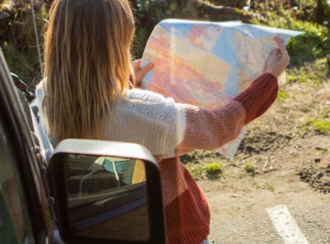 Woman holding a map - link to view insurance info by state from The General Insurance quote page.