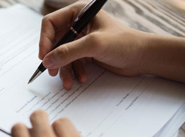 Hand signing a contract - link to SR-22 insurance information from The General Insurance quote page